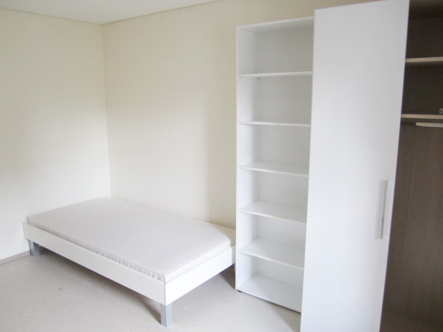 Möbliertes Zimmer mit Bett, Bücherregal und Kleiderschrank – Studentenwohnheim Eichenforst Amberg